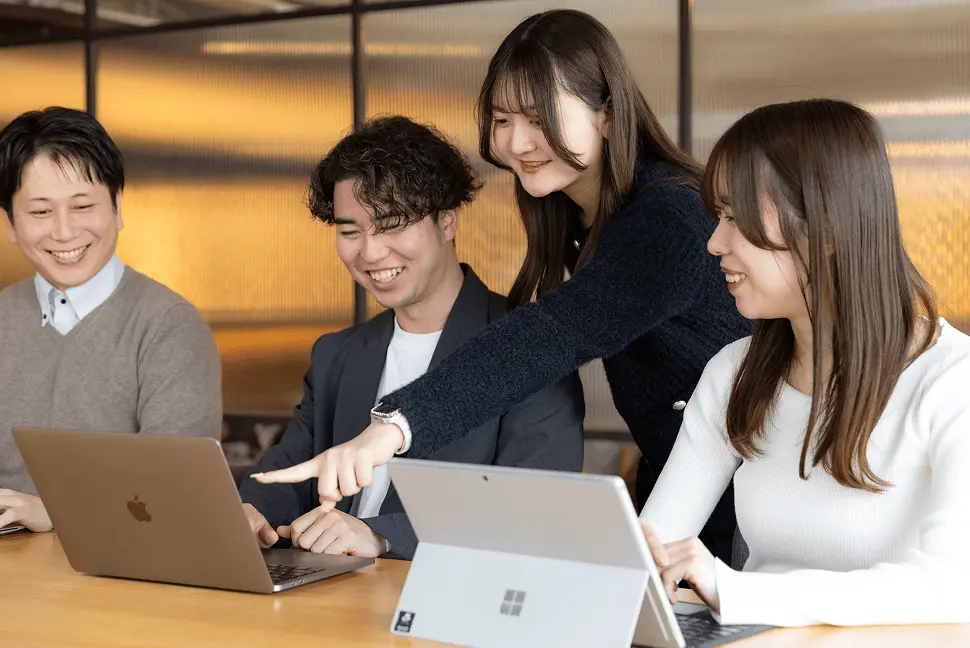 ノートパソコンを囲んで会話する4人