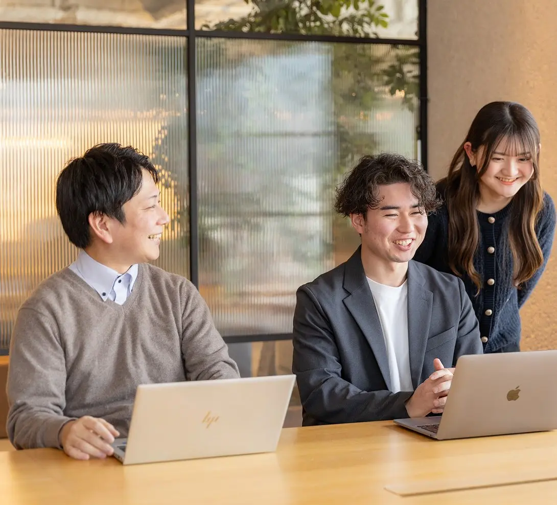 笑顔で話し合う３人の社員